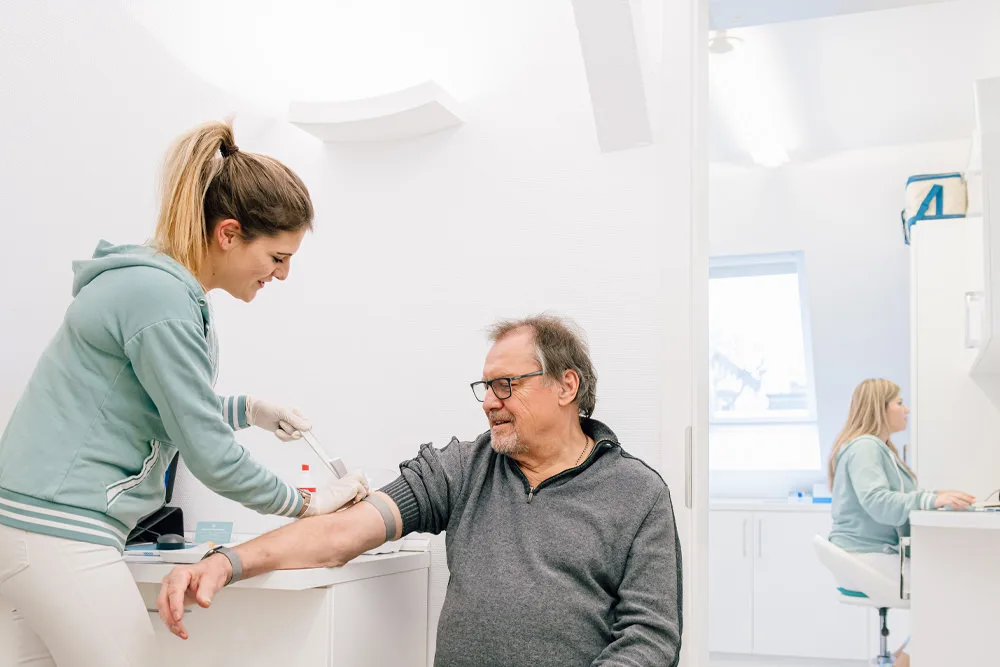 Medizinische Fachangestellte nimmt einem Patienten Blut ab