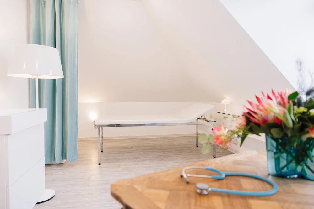 Behandlungszimmer mit Untersuchungsliege und Blumenstrauß