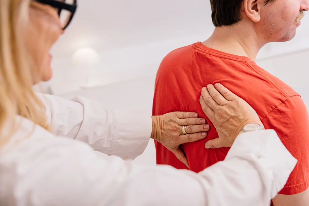 Ärztin untersucht den Rücken eines Patienten
