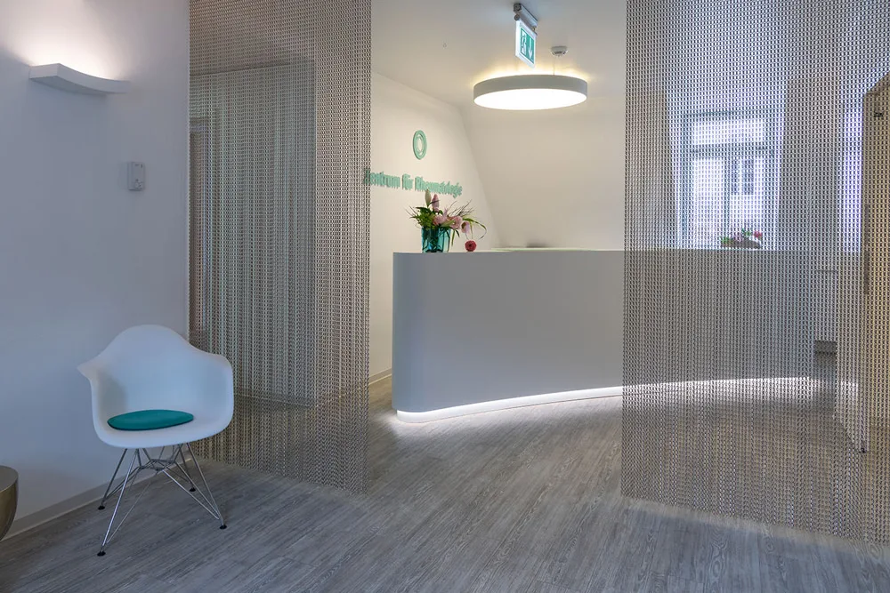 Empfangstresen des Zentrums für Rheumatologie mit Logo an der Wand