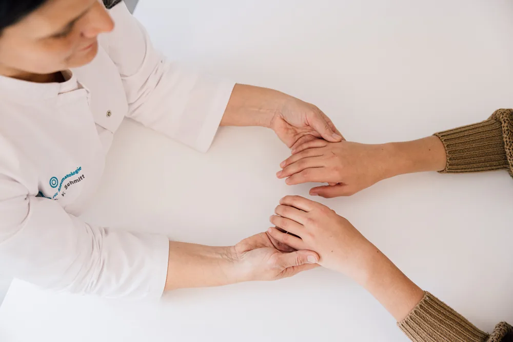 Ärztin untersucht die Hände einer Patientin