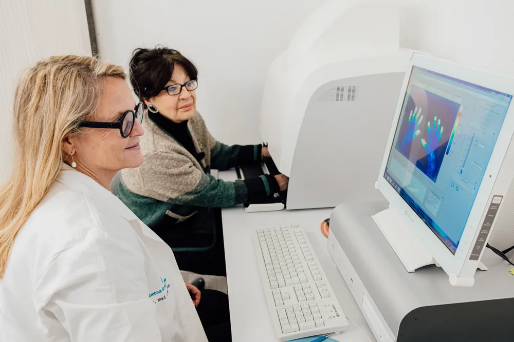Doctor and patient at the Xiralite examination: the screen shows the fluorescence optical image of both hands